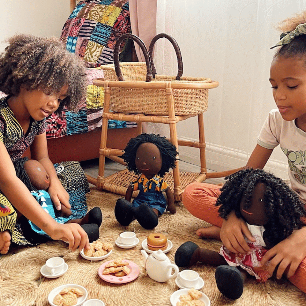 Children playing with african dolls and toys on a carpeted floor.