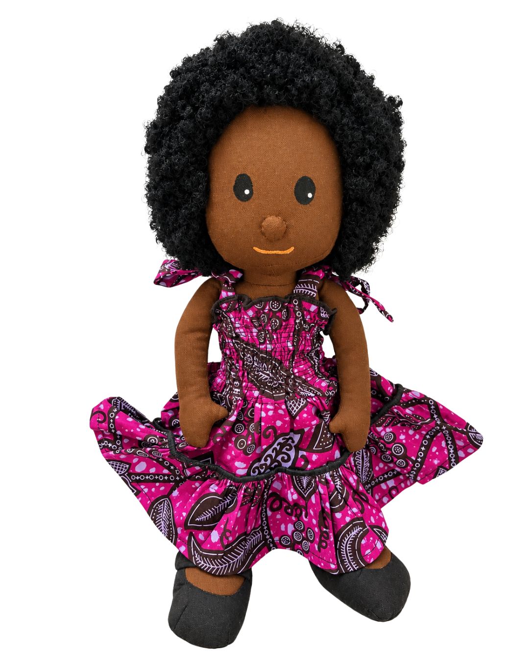 A handmade African American doll with black curly hair, wearing a pink and black patterned dress and black shoes, set against a plain white background.