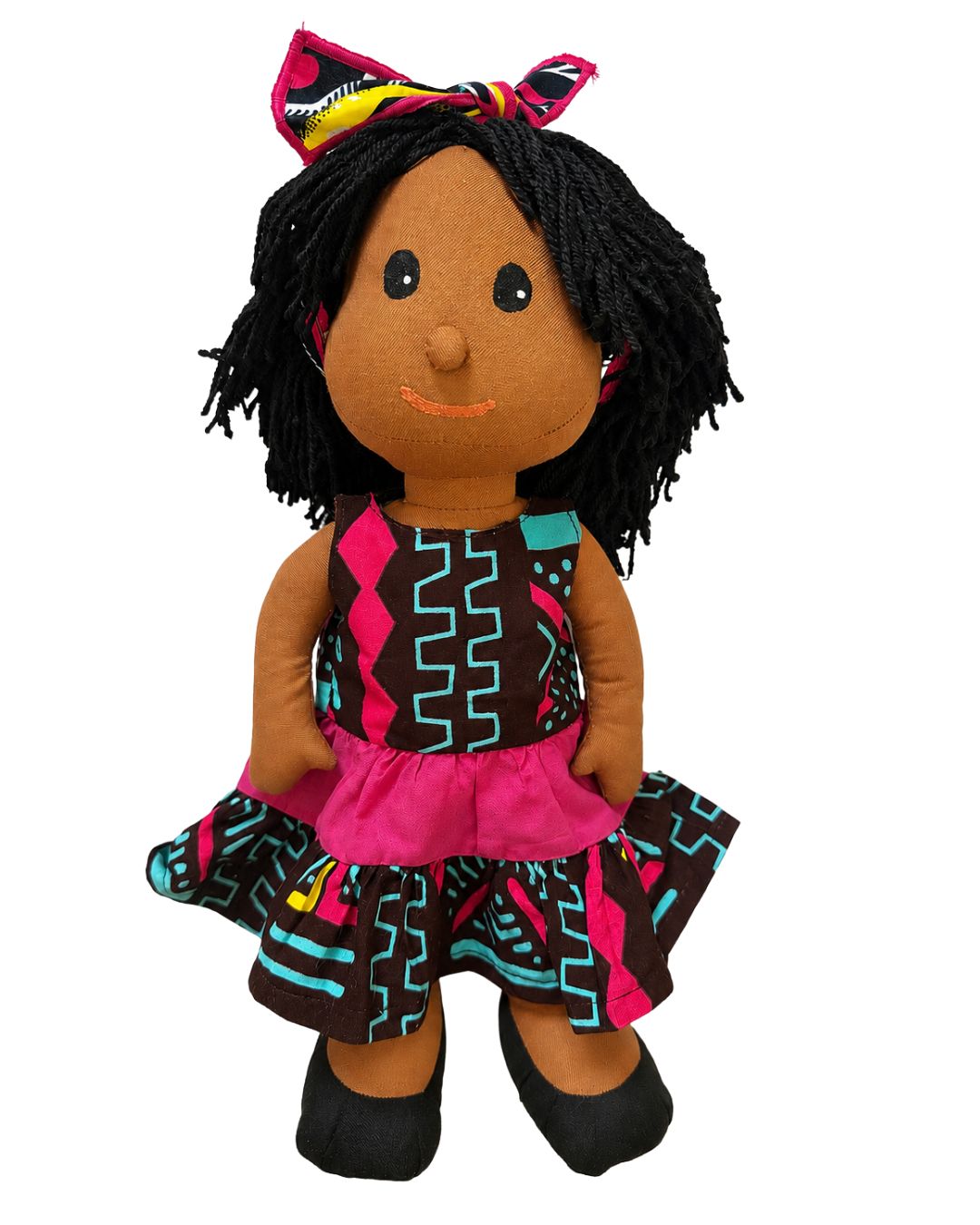 A handmade African wax print doll with black yarn hair, a pink and black patterned dress, and a matching hair bow, set against a plain white background.
