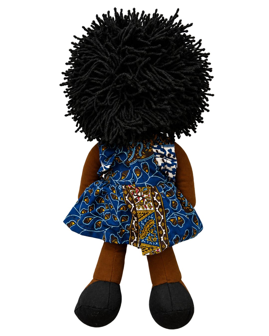 A handmade African doll with a large black yarn afro, wearing a blue patterned dress with brown and gold details, set against a plain white background.