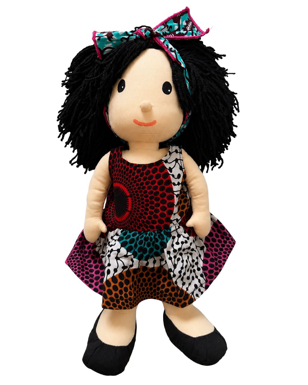 A handmade plush doll with black yarn hair, a colorful patterned dress, and black shoes, isolated on a white background.