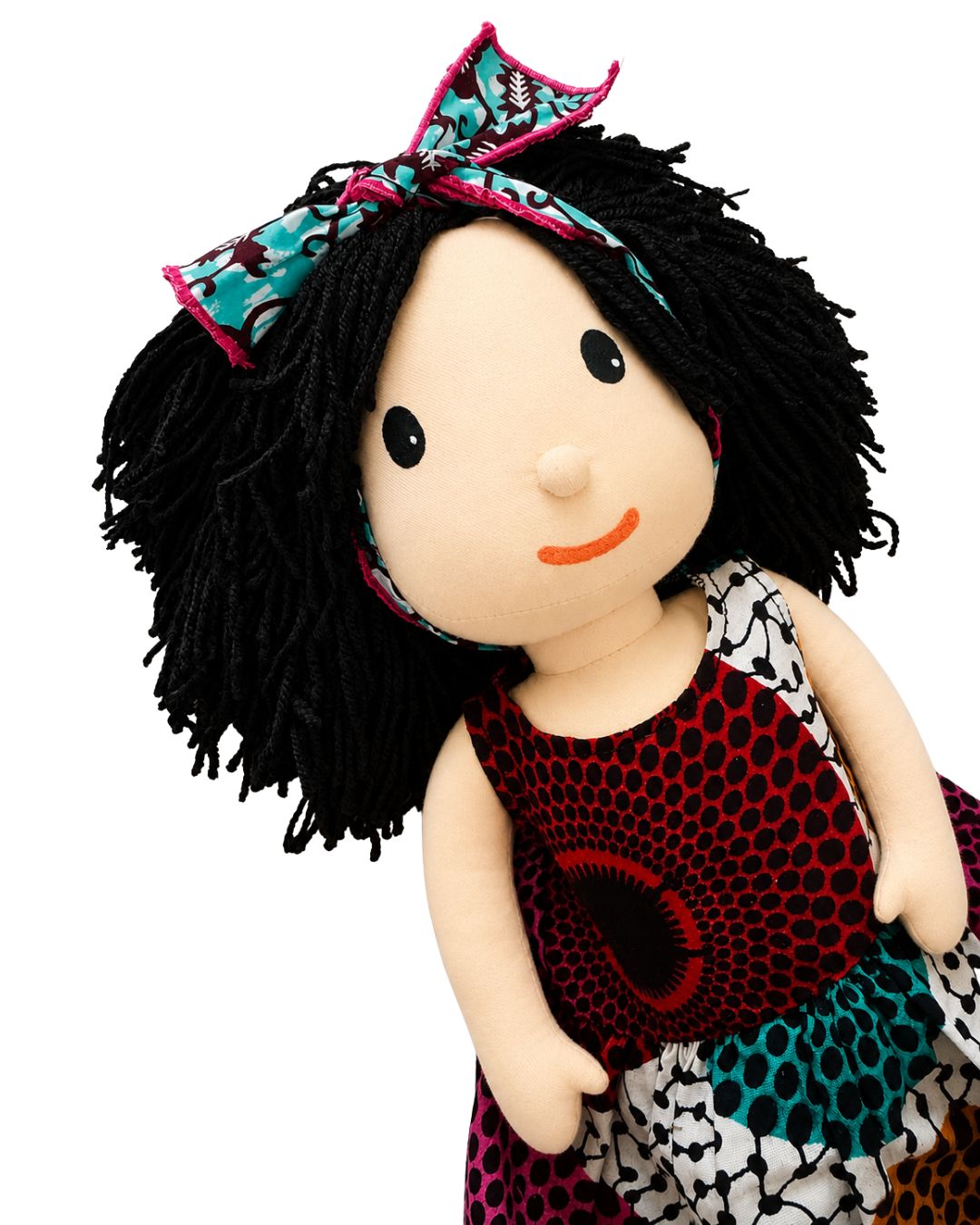 A handmade fabric doll with black yarn hair, a patterned headband, and a red, black, and teal patterned dress, shown against a plain white background.