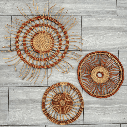 Three woven wall art pieces on a wooden surface