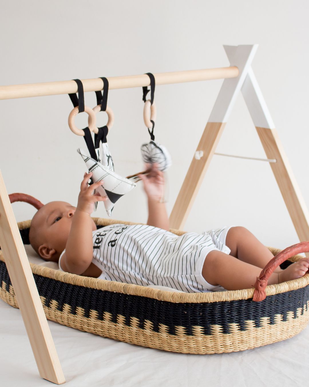 Woven baby basket used under an activity gym during supervised play