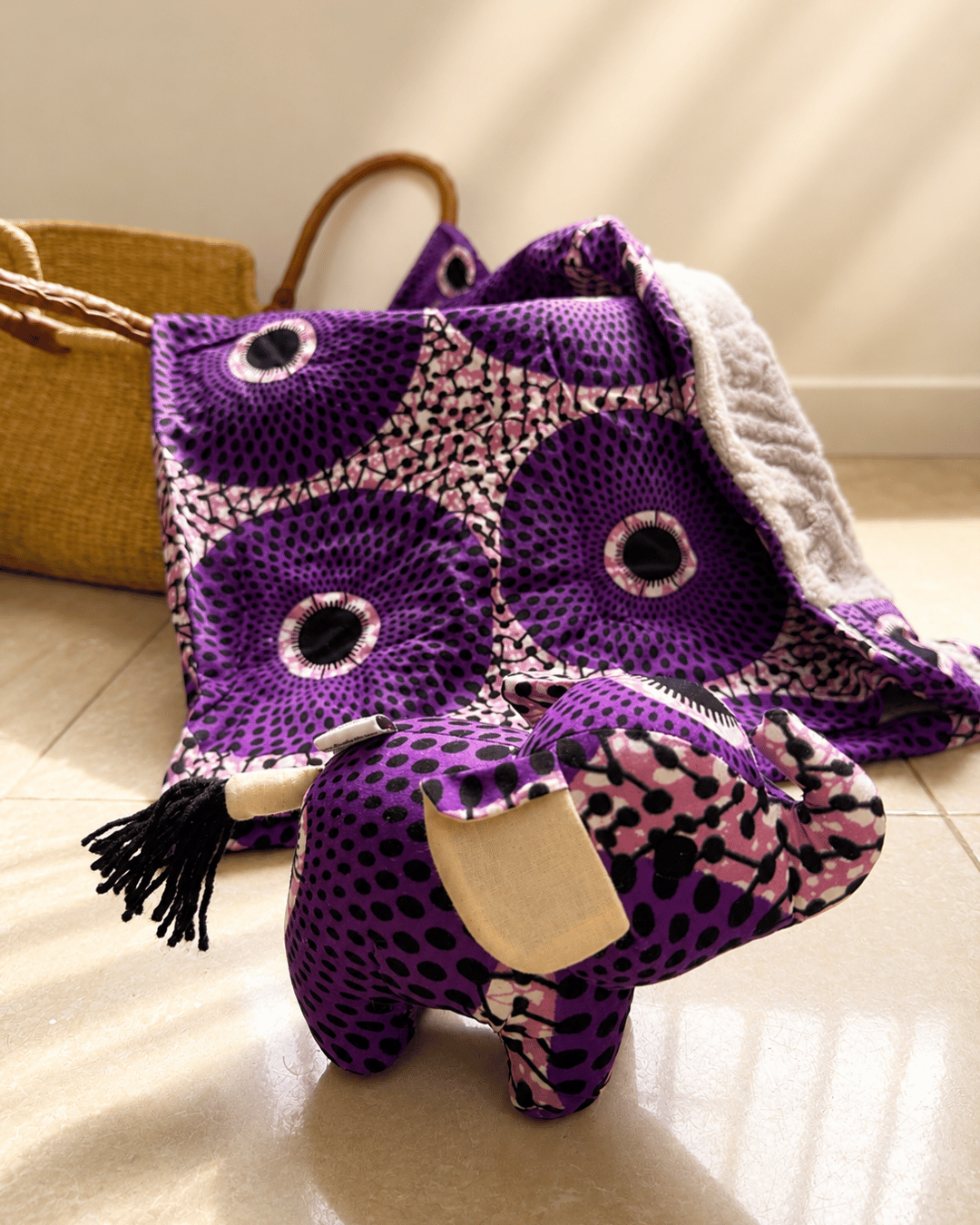 Purple and pink patterned bag with a matching pouch on a light wooden floor.