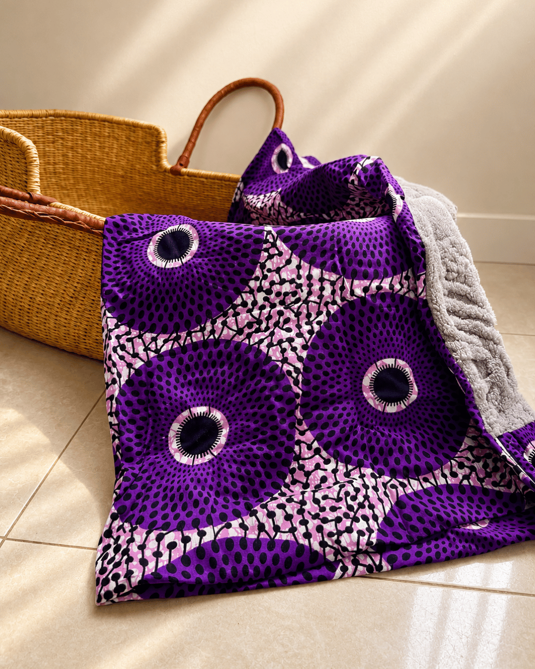 Purple patterned blanket with a woven basket on a light wooden floor