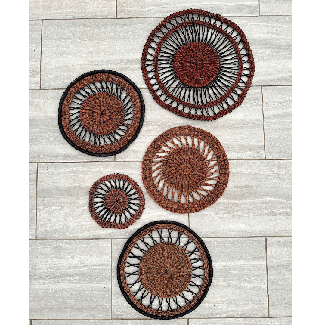 Set of five brown and black woven wall baskets on a light wood panel background