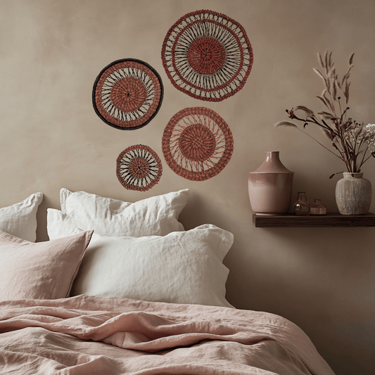 Decorative wall art above a bed with pillows and a shelf holding vases and a plant.