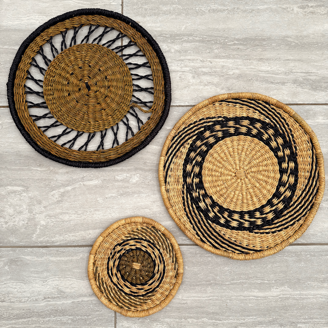 Three woven baskets with black accents on a wooden surface