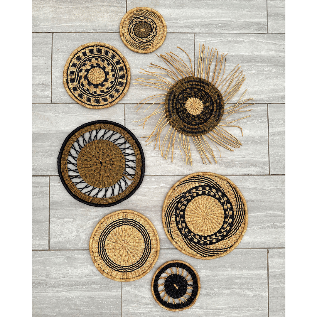 Set of woven baskets with black and gold patterns on a light wooden floor.